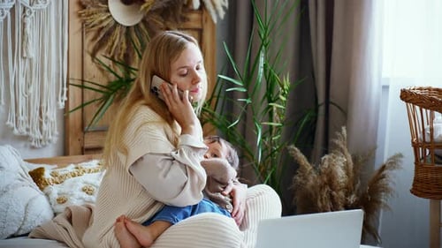 Schöne junge Mutter, die aus der Ferne im Heimbüro arbeitet und Baby stillt