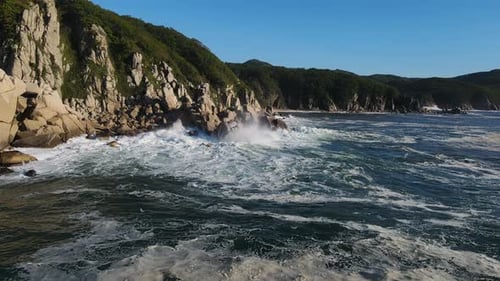 Aerial Large Waves Rolling Onto the Rocky Coast at Dawn