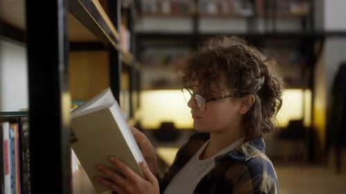Young Adult Reads Book in Library