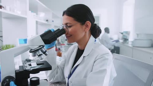 Female Scientist Examines Sample with Microscope in Lab