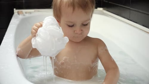 Blonde Child Bathtime Fun with Sponge