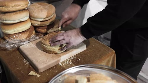 Close-up Man Cutting Round Bread Loaf on Table