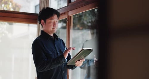 Man Using a Tablet Inside Next to Window