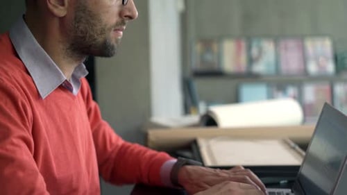 Young entrepreneur works from home on laptop at table in modern apartment