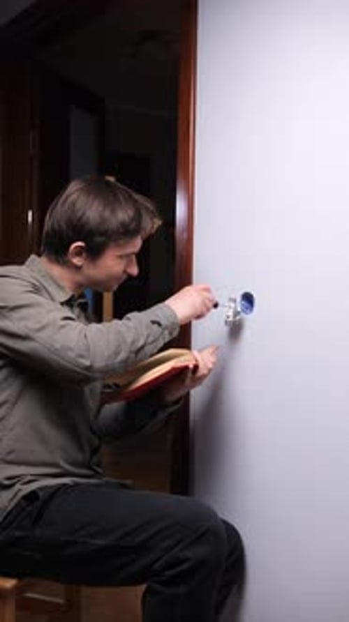 Young Adult Works on Electrical Box with Screwdriver
