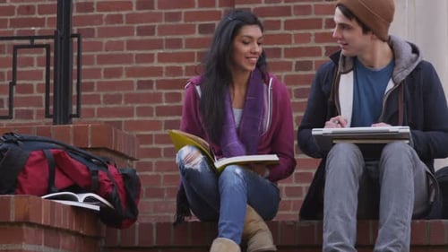 College students studying together on campus in autumn with vibrant fall leaves