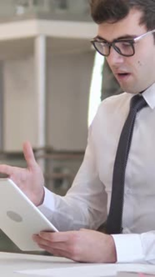 Thoughtful Young Adult Works on Tablet at Desk