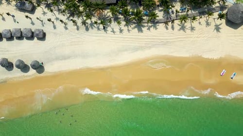 Bird's eye drone shot over tropical beach resort with turquoise waters and sand beach