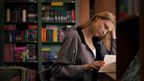 Close Up in Bookstore Near the Window a Beautiful Student is Sitting Reading Books Preparing for