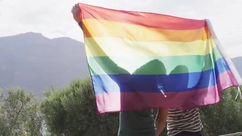 Two Young Adults Holding Pride Flag Together