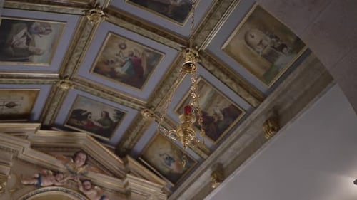 Ornate church ceiling with religious paintings and a hanging chandelier.