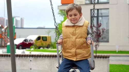 Young Boy Swinging Happily on Playground Swing