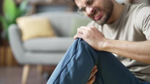 Close up. Male hands holding massaging knee during a gymnastics workout sitting on the floor
