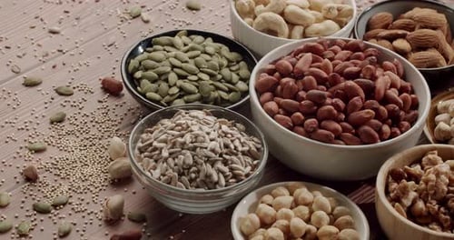 Healthy Nuts and Seeds Assortment Sliding on Wooden Table