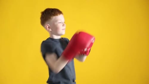 Junge mit Boxhandschuhen trainiert auf gelbem Hintergrund. Sport für Kinder