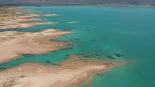 Scenic Drone Shot of a Lake with Dry Land and Clear Water – 4K