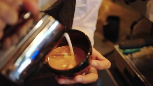 4K Close up of Barista hand pouring froth milk in espresso coffee making coffee latte in coffee cup.