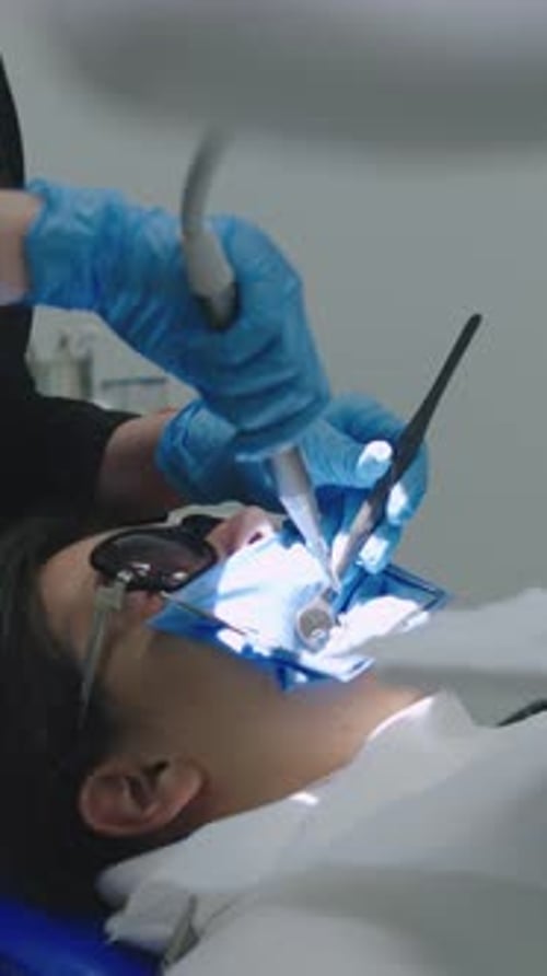 Patient Receives Dental Treatment in a Clinic While Dentist Checks Teeth and Performs a Procedure