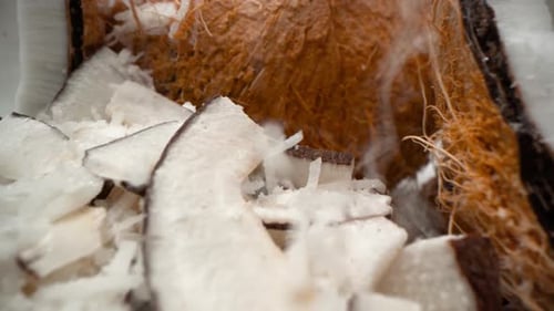 Kokosnüsse und zerkleinerte Kokosflocken aus der Nähe, fallen in den Turm, Zutaten ziehen ein 4k-Lebensmittelprodukt weg
