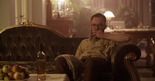 Man with Beard Sitting and Sipping Alcohol