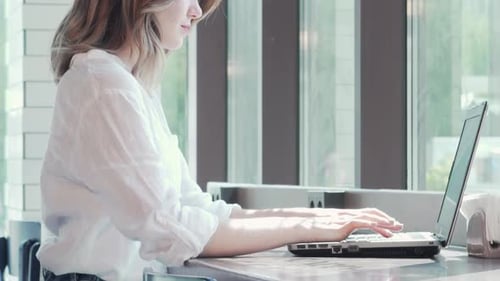 Dynamic Shot of a Beautiful Woman Immersed in Her Laptop at a Cozy Coffee Shop
