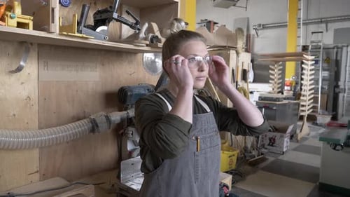 Young woman carpenter prepares for woodwork project in community workshop