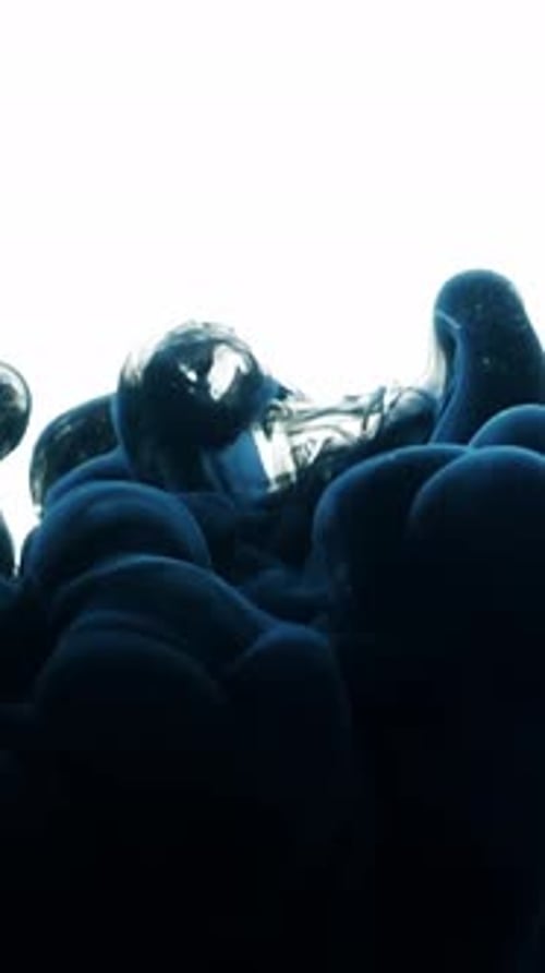Swirling Blue Ink Underwater Against a White Background