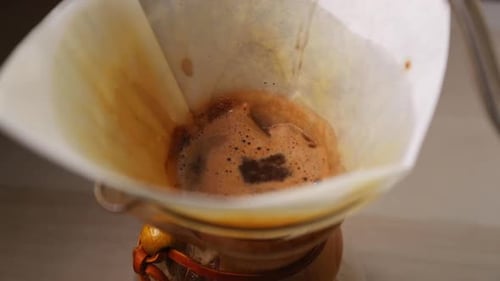 Watering the coffee pot with a view of a white filter placed in a glass jar for dripping coffee pour
