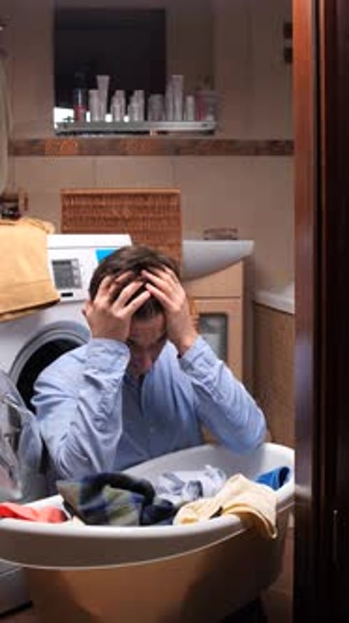 Vertical Video a Stressed Man Struggles with Household Chores Holding His Head in Frustration While