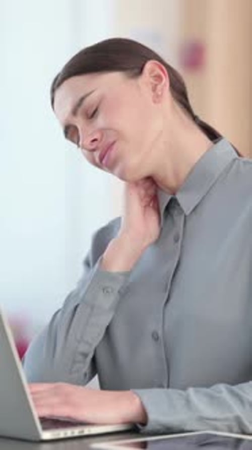 Tired Woman Massaging Neck at Desk