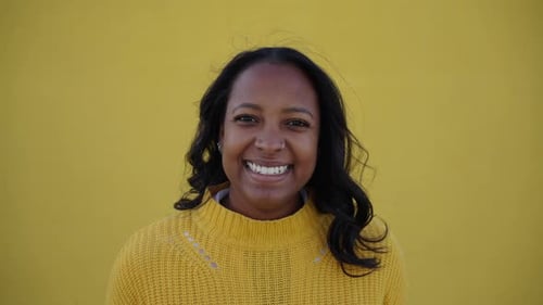 Smiling Woman in Yellow Sweater in Front of Yellow Background
