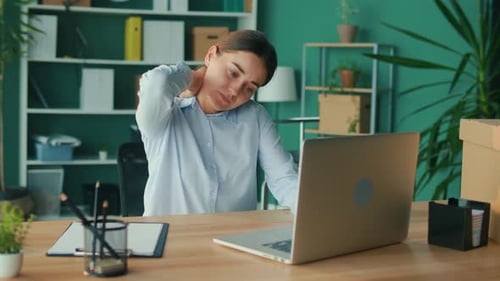 Woman Massages Neck While Working at Desk