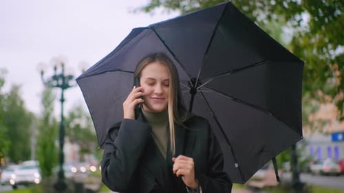 Woman Walking with Umbrella and Talking on Phone