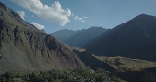 Cinematic drone aerial of a rugged mountain slopes and rocky ridges under clear blue sky, revealing