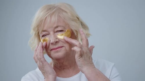 Senior Woman Applies Under Eye Patches for Skincare
