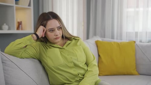 Pensive Young Woman Sitting on Sofa