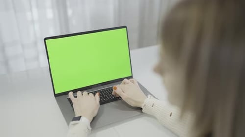 Woman Typing on Laptop with Green Screen on the Office Table