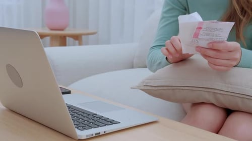 Closeup hand asian woman sitting on sofa worried with bills about financial and stress at home.