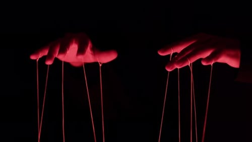 The Puppeteer Controls the Puppets in the Theater in Red Neon Light Closeup Managing People at Work