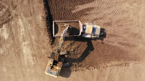 Excavator Loading Dirt Into Dump Truck Aerial