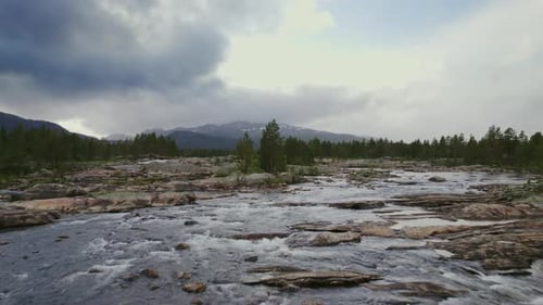 Serene River Flowing Through Rocky Terrain With Mountains In The Background
