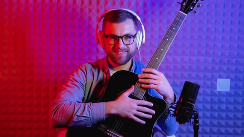 Bearded Man Smiling, Holding Guitar in Music Studio