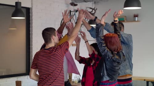 Joyful multi ethnic friends giving high five in cafe slow motion