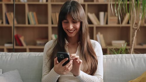 Happy Woman Using Mobile Phone on Sofa Indoors
