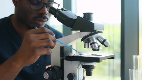 Researcher Uses Microscope and Records Data in Lab