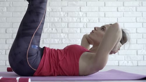 Frau trainiert, macht zu Hause Crunches auf der Matte, Ansicht von oben