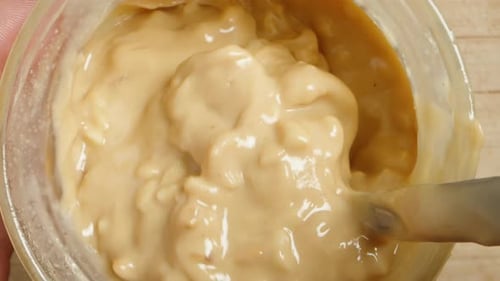 Stirring Peanut Butter with Nut Pieces, Spoon in Close-Up. Dolly slider