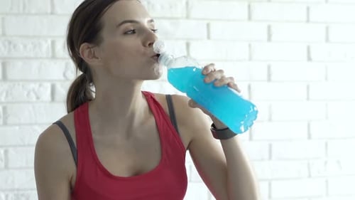 Young Woman Drinks Blue Sports Drink After Workout