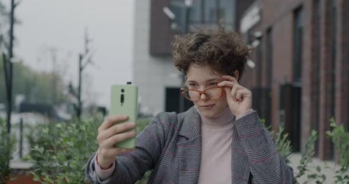 Woman Smiling and Posing with Phone Outdoors