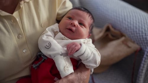 Adorable Newborn Infant Yawns in Grandmother's Arms